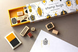 Box, wooden stamps, ink pad and paper with sample bug print.