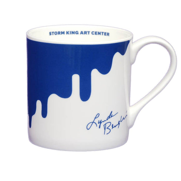 White mug with dripping blue paint and Lynda Benglis' signature.