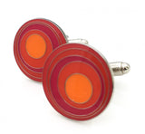 Round cufflinks with orange circular pattern.